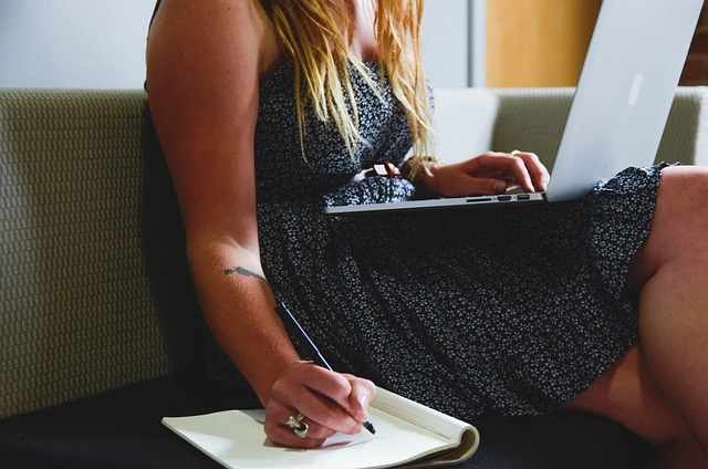 une entrepreneure qui écrit sur un carnet et est sur son ordinateur portable